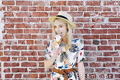 Blond Caucasian Girl Licks Ice Cream Against a Brick Wall Cone Fedora Hat Stock Photo