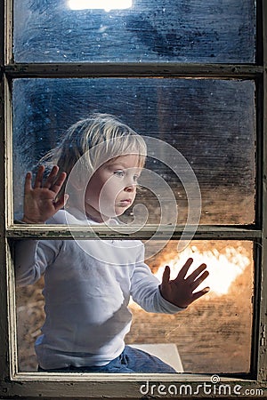 Blond child behind the window, looking outside Stock Photo