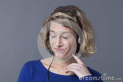 Blond female bored wearing earphones with eyes closed Stock Photo