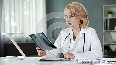 Blond female doctor examining X-ray picture, medical profession, diagnosis Stock Photo