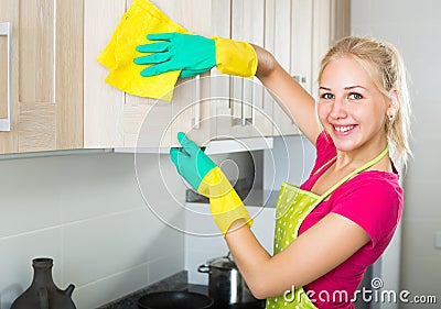 Blond girl cleaning surfaces at kitchen Stock Photo