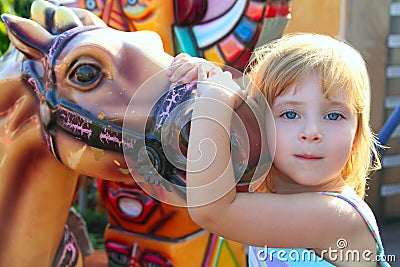 Blond girl with fairground horse enjoy in park Stock Photo