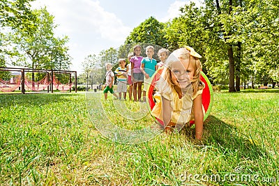 Blond girl and her friends play in tube on lawn Stock Photo