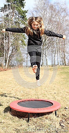 Blond girl jumping on trampoline Stock Photo