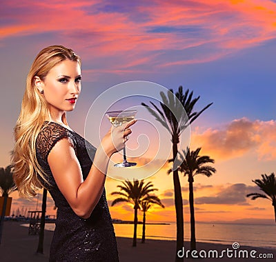 Blond girl sunset Arenal beach drinking vermout Stock Photo