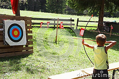 Blond hair kid playing archery during children summer games Stock Photo