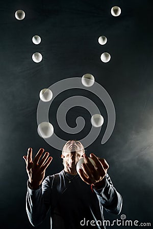 Blond juggler with white balls on black background Stock Photo