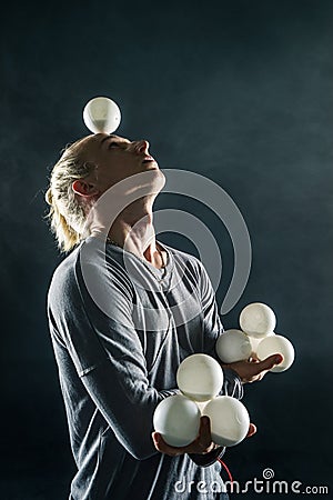 Blond juggler with white balls on black background Stock Photo