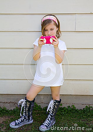 Blond little fashion kid girl playing with smartphone Stock Photo