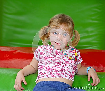 Blond little girl resting on colorful playground Stock Photo