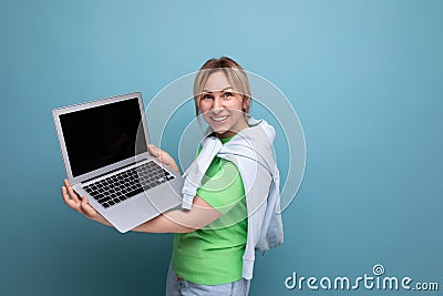 blond positive attractive girl in casual outfit shows screen with mockup on laptop on blue background Stock Photo