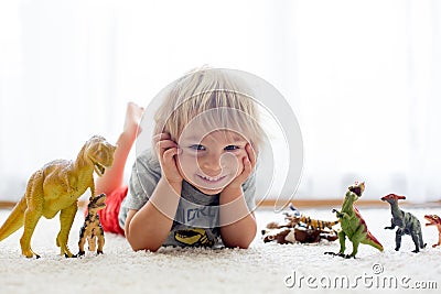 Blond toddler child, playing with dinosaurs at home Stock Photo