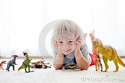 Blond toddler child, playing with dinosaurs at home Stock Photo