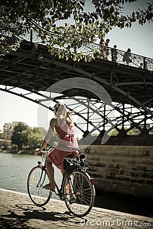 Blond woman with bike under the bridge of arts in Paris Editorial Stock Photo