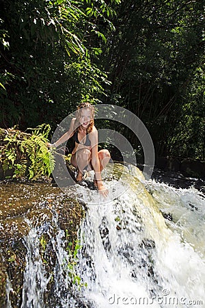 Blond woman in bikini by waterfall Stock Photo