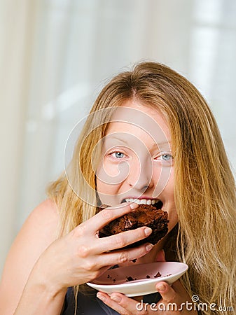 Blond woman biting a chocolate brownie Stock Photo