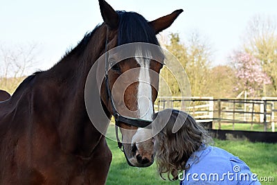 Blond woman cuddles with her horse Stock Photo