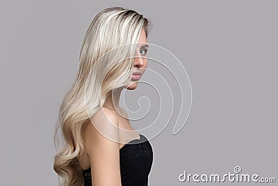 Blond woman on gray background. Hair care and coloring concept. Copycpase Wavy Hairstyle Stock Photo