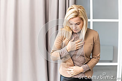 Blond woman having a stomachache at home. Stock Photo