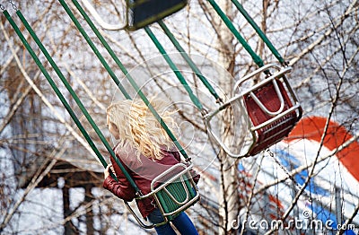 Blond woman riding on a chain swing Stock Photo