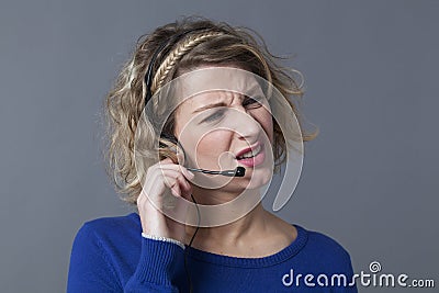 Blond woman squinting while responding to customer Stock Photo