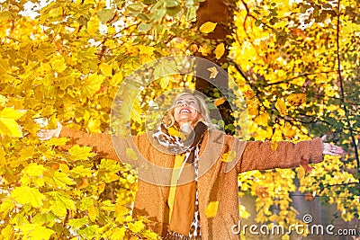 Blond woman standing beneath a tree and enjoying the autumn weather Stock Photo