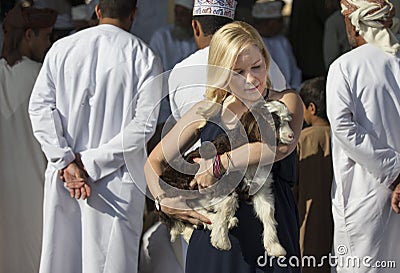 Blonde with a baby goat at habit market in Nizwa Editorial Stock Photo
