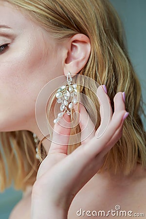 The blonde bride straightens the earrings. Morning of the bride Stock Photo