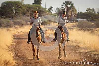 Blonde and brunette ride horses along track Stock Photo