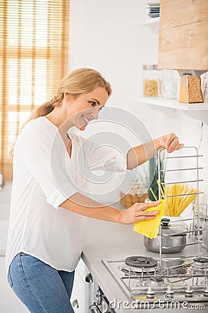 Blonde cute housewife cleaning a stove in the kitchen Stock Photo