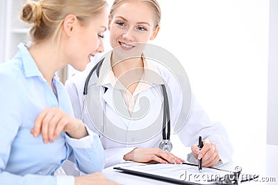 Blonde female doctor and patient talking in hospital office. Health care and client service in medicine Stock Photo