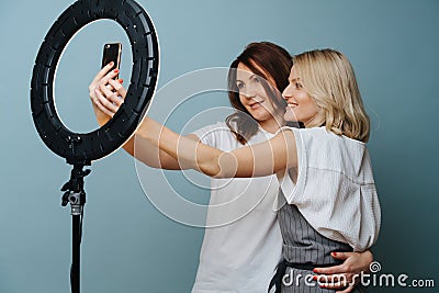 Female stylist is taking selfie with a client with the help of ring lamp Stock Photo
