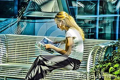 A Blonde female sitting reading a magazine Editorial Stock Photo