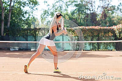 Blonde female tennis player in action. View from back. Stock Photo