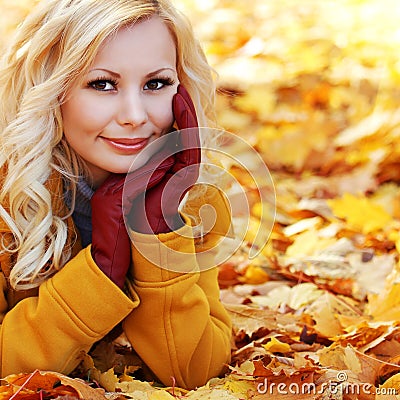 Blonde girl in Autumn Park with Maple leaves. Fashion Stock Photo