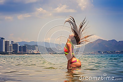 Blonde girl in bikini stands in sea shaken head lifts hair up Stock Photo