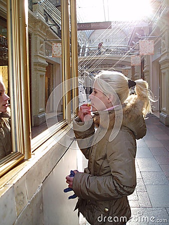 Blonde girl with blond hair paints her lips with lipstick near the window Stock Photo