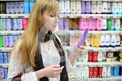 Blonde girl chooses shampoo in large store Stock Photo
