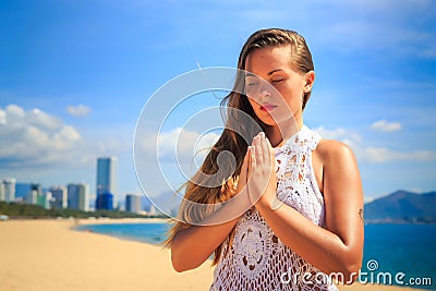 blonde girl in lace sits in yoga asana thunderbolt on beach Stock Photo