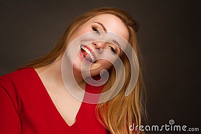 A blonde girl with an overweight plus size, in a red overallposing on a dark Studio background Stock Photo