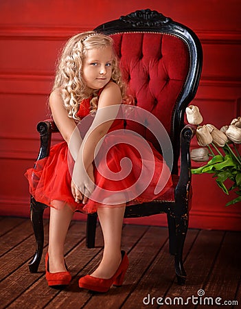 little girl with blond in a red dress in a red room Stock Photo