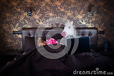 Blonde girl sleeping with funny man in comical mask. Unusual couple Stock Photo