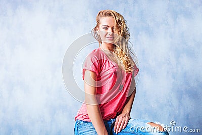 Blonde girl smiling and sitting with rugged jeans and messy hair Stock Photo