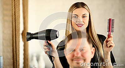 Blonde Hairstylist Using Dryer and Comb for Man Stock Photo