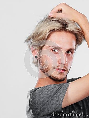 Blonde handsome guy touching his hair Stock Photo