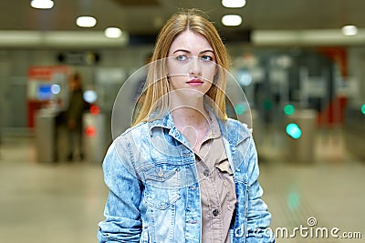 Blonde with long hair stands near the turnstiles at subway station Stock Photo