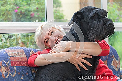 Blonde middle-aged woman is embracing the dog Stock Photo