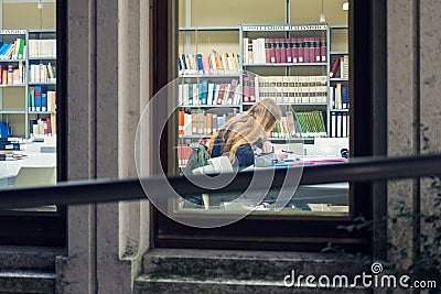 Blonde student reading book in library at night Editorial Stock Photo