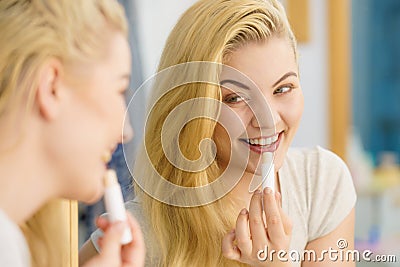Woman in bathroom applying lip balm Stock Photo