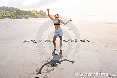 Blonde woman on a beach with inscriptions in the sand gesturing to be happy Stock Photo